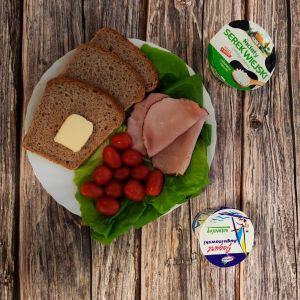 Zdjęcie przedstawia Dietę z ograniczeniem łatwoprzyswajalnych węglowodan&oacute;w: Chleb Graham Masło extra Serek wiejski ziarnisty Kawa zbożowa z mlekiem Jogurt naturalny Sałata zielona Pomidorki koktajlowe Szynka pieczona w ogniu wieprzowa